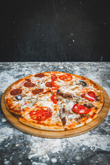 Slices of italian pizza on abstract dark background with wheat flour.