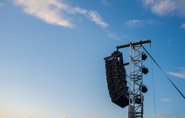 Line array speaker system hanging from pole during daylight performance