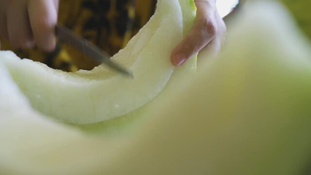 Cutting exotic melon fruit. Close-up view of a woman hands slicing sweet melon. Hand of person cuts muskmelon