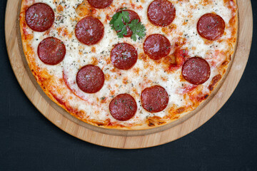 Pizza pepperoni, mozzarella, oregano on a black background.