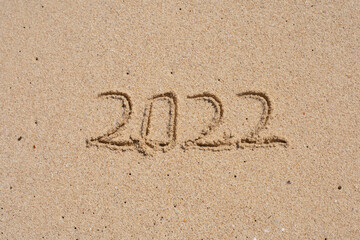 wooden cube written 2022 on the beach sand.