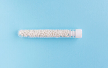 Homeopathic pills and plastic container on a blue background. Homeopathic medicine