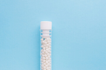 Homeopathic pills and plastic container on a blue background. Homeopathic medicine