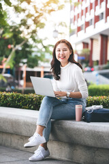 Female college students sit happily working outdoors after school. On campus at sunset with warm light