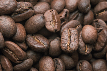 Closeup of coffee beans at roasted coffee heap. Coffee bean on macro ground coffee background. Arabic roasting coffee - ingredient of hot beverage