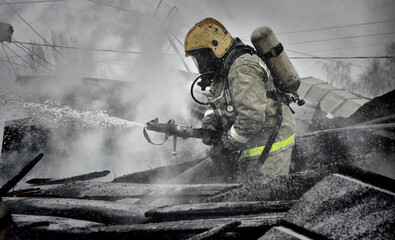 Firefighters with the inscription on the back in Russian " fire protection. Emercom of Russia" extinguish a fire on the roof of a house on a frosty winter day