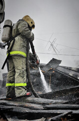 Firefighters extinguish a fire on the roof of a house on a frosty winter day