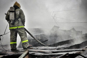 Obraz premium Firefighters extinguish a fire on the roof of a house on a frosty winter day
