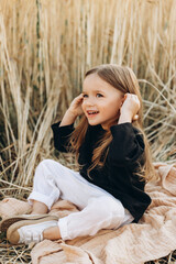 pretty 3-year-old girl walks and poses for a photo in a wheat field at sunset