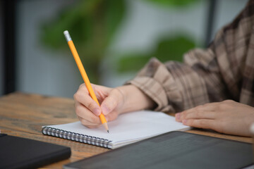 Fototapeta na wymiar Female hands with pencil writing on notebook.
