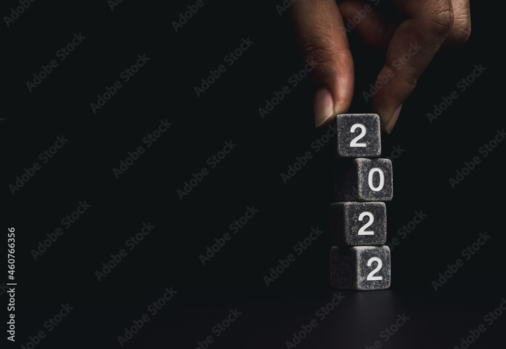Poster 2022 happy new year with the business goal concept. hand putting a black dice on the top of the 2022