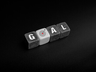 Goals concept. Goal, word and target icon sign on black and white cube blocks and arrow arranging on dark background, top view.