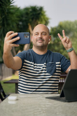 Worker man doing the symbol of victory while talking selfie in a park