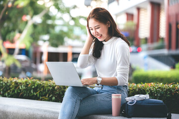 Female college students sit happily working outdoors after school. On campus at sunset with warm light