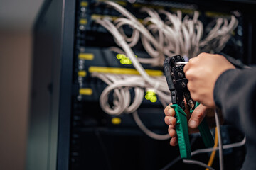 Fototapeta premium Technician installing a new connector on ethernet cable using crimping tool.