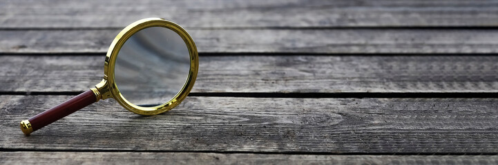Magnifying glass on wood background with copy space for text.