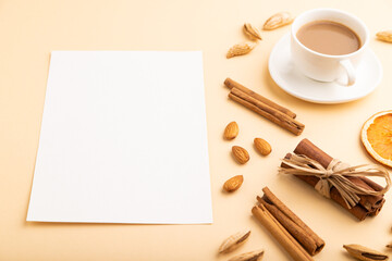 Composition with white paper sheet, almonds, cinnamon and cup of coffee. mockup on orange background. side view, copy space.