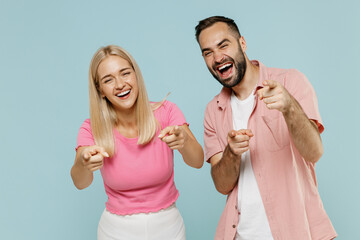 Young fun couple two friends family man woman in casual clothes point fingers camera on you joking laugh camera together isolated on pastel plain light blue background studio People lifestyle concept. - obrazy, fototapety, plakaty