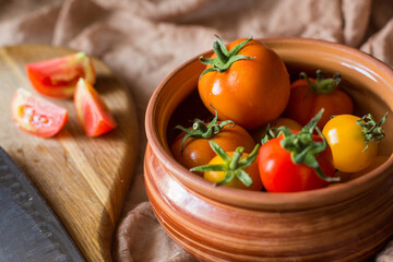 Fresh tomatoes in earthenware. Red, orange and yellow tomatoes on a brown background. Picking tomatoes