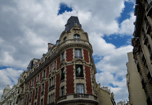 Immeuble ancien en briques et pierre. Ciel nuageux. Paris.