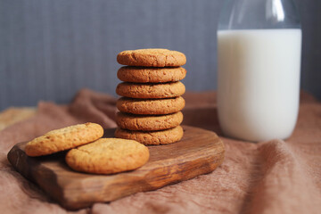 cookies on a wooden board and milk in a glass bottle