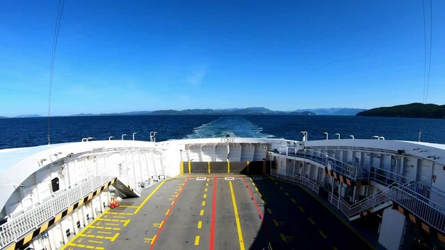 Stern panoramic view from deck of ferry Lysøy - Gas and electricity powered ship -  Handheld static shot showing empty ferry deck underway between Halhjem and Sandvikvåg in Norway