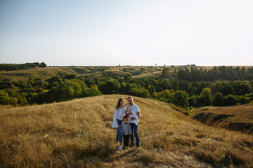 Fototapeta na wymiar family with small children on a background of hills among a field of grass