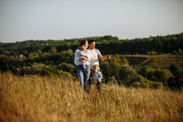 family with small children on a background of hills among a field of grass