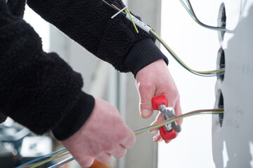 Elektriker bearbeitet Elektro Dr&auml;hte mit Zange f&uuml;r Elektroinstallation in Neubau Geb&auml;ude