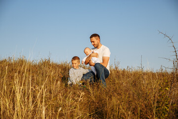 Naklejka na ściany i meble dad is talking to his sons on a background of grass and sky