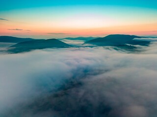 Fog in the mountain valley at dawn. Ukrainian Carpathians in the morning in the haze. Aerial drone view.