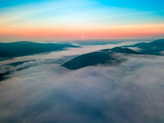 Fog in the mountain valley at dawn. Ukrainian Carpathians in the morning in the haze. Aerial drone view.