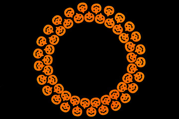 Bright orange pumpkins are arranged in a circle in two rows, forming a frame on a black background. Jack's lamp for a terrible holiday. Dark background with a place for Halloween text, for design. 