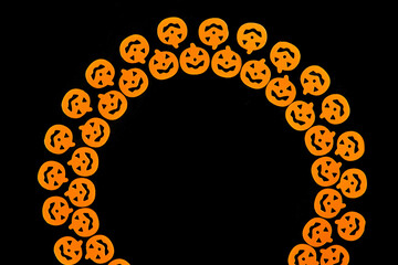 Bright orange pumpkins are arranged in a semicircle in two rows, forming a frame on a black background. Jack's lamp for a holiday. Dark background with a place for Halloween text, for design. 
