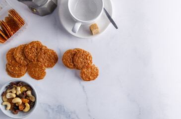 Homemade almond snaps. Homemade almond raisins snaps served with a coffee on the side. Presented on a white marble table top.