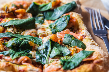 Homemade pizza with salmon, pesto and shrimps. Comfort food concept.