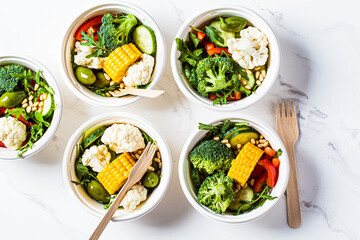 Vegan vegetable salad in paper take away bowls. Eco-friendly recyclable tableware, zero waste concept.