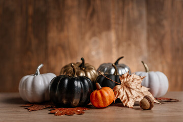 Decorated golden, black and natural pumpkins on wooden background