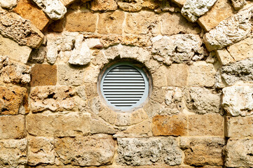 round plastic ventilation grate in the stone wall