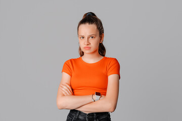Angry brunette teen girl feel unfair and displeased, cross arms on chest and frowning, condemn...