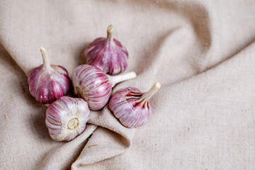 The purple garlic heads lie on the burlap. Spices for cooking. Elements of a vegetarian and healthy menu.
