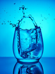 Creative splashing water in the glass on blue background. 