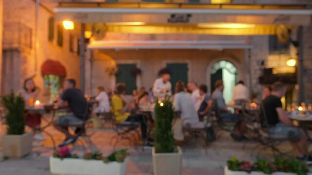 Defocused scene of people having dinner in outdoor restaurant at evening