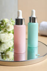 Bottles of cosmetic products and mirror on beige table