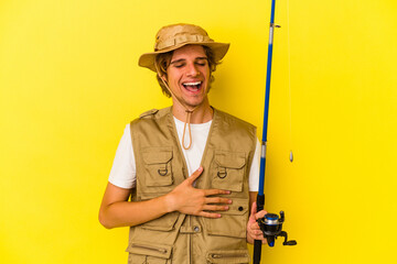 Young fisherman with makeup holding rod isolated on yellow background  laughing and having fun.