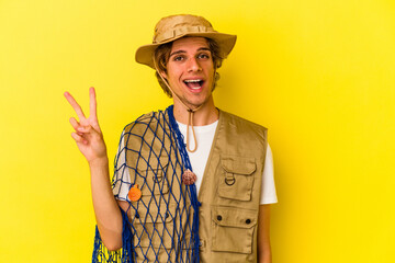 Young fisherman with makeup holding a net isolated on yellow background  showing number two with fingers.