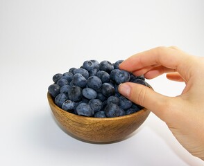 ripe blueberries in a wooden bowl on a white background