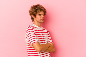 Young caucasian man with make up isolated on pink background frowning face in displeasure, keeps...