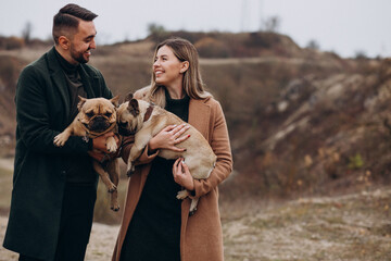 Young couple walking their french bulldogs in park