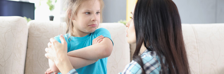 Sad offended daughter sitting on couch, turning back to mother after quarrel at home